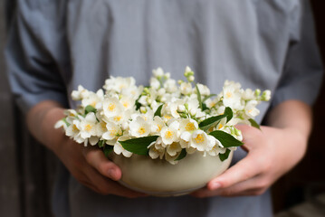 Man holding a vase with white jasmine flowers	