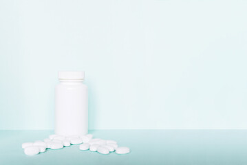 white pills and a plastic container on a blue background. Medical theme.	