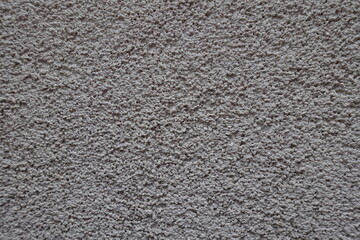 Close view of dusty wall with coarse light gray roughcast finish