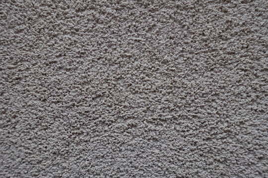 Close shot of dusty wall with coarse light gray roughcast finish