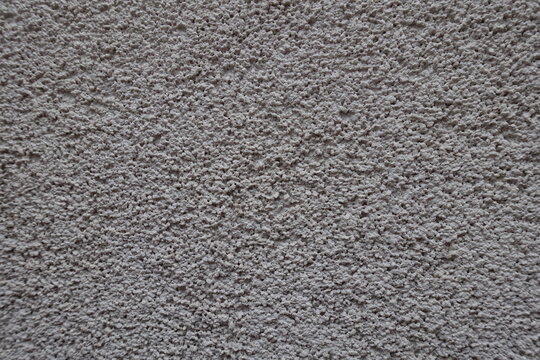 Close view of dusty wall with coarse light gray roughcast finish