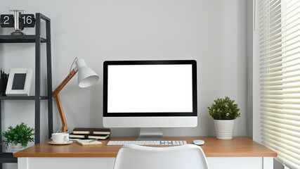 Modern home office interior with blank computer screen on wooden desk. Empty screen for your advertising and creative design