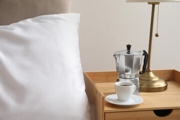 Fototapeta na wymiar Geyser coffee maker and cup of espresso on nightstand near bed