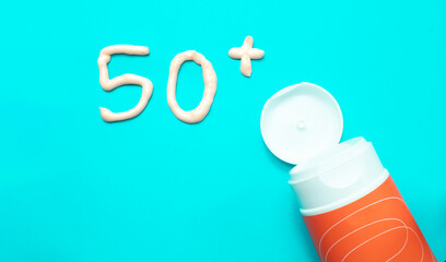 A tube of sunscreen on a bright light blue background with 50+ written on it.