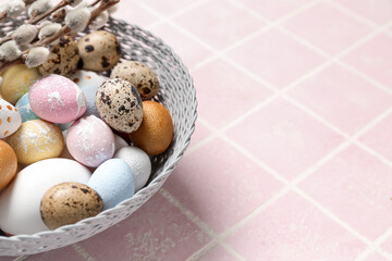 Bowl of beautiful Easter eggs on color tile, closeup