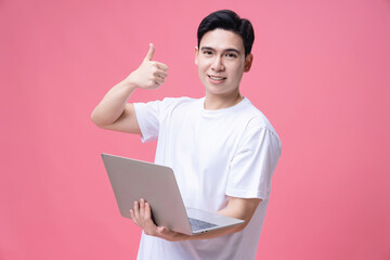 Young Asian man holding laptop on background
