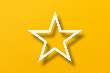 paper cut star shape with light and shadow placed on a yellow paper background