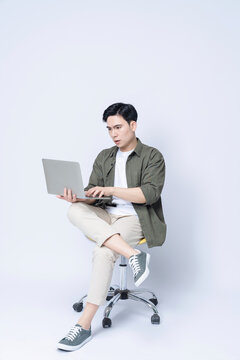 Young Asian business man sitting on chair and using laptop on background