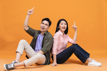 Young Asian couple sitting on background