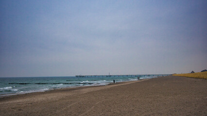 Blick &uuml;ber den Sandstrand auf die Seebr&uuml;cke Wustrow. Weite K&uuml;stenlandschaft am Fischland-Dar&szlig; bei bew&ouml;lktem Himmel, Mecklenburg-Vorpommern, Deutschland