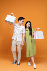 Young Asian couple holding shopping bag on background