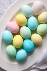Plate with beautiful painted Easter eggs on light background, closeup