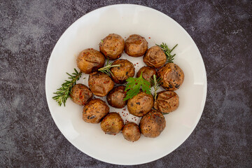 Fried (baked) whole small potatoes with rosemary and salt in a frying pan, ruddy crust, appetizing food