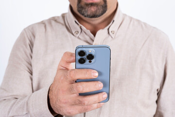 Using modern smartphone, cropped image of male using modern smartphone. Blue mobile phone with three cameras. Isolated on white background. Holding cell phone with one hand. Wearing casual shirt.