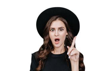 Great idea! Attractive hispanic young woman in black hat and black t-shirt with wide open eyes and mouth raises index finger with surprised face against transparent background. Look up, that's amazing