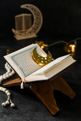 Rehal with Koran, prayer beads and glowing lights for Ramadan on dark background
