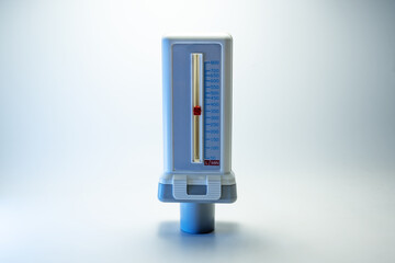 Peak flow meter, medical device that measures the maximum rate of exhalation of a person to monitor lung function and breathing. Light background, copy space, selected focus