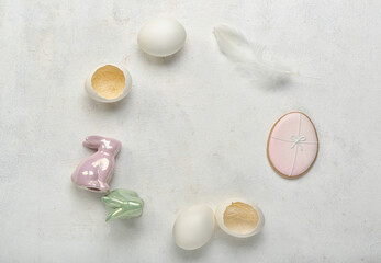 Frame made of Easter eggs and bunnies on grey background