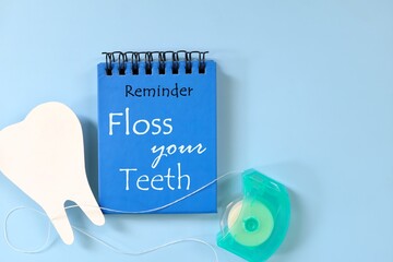 Floss your teeth reminder on blue notepad. Dental and oral health care concept.