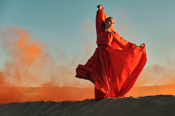 Woman in red dress dancing in the desert