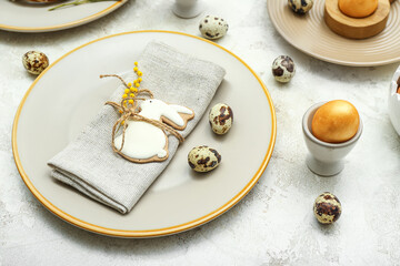 Table setting with Easter eggs, mimosa flowers and cute bunny cookie on white grunge background