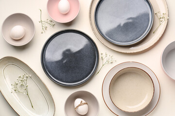 Composition with set of plates, Easter eggs and gypsophila flowers on white background