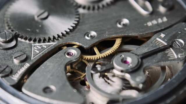 Mechanism of vintage stopwatch close-up. Round clock watch mechanism working in macro. Old retro clockwork gears, cogwheels, and pendulum movement inside the ancient stopwatch.