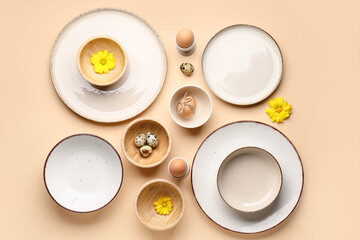 Set of crockery with Easter eggs and chrysanthemum flowers on beige background