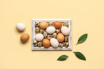 Frame with Easter eggs and green leaves on beige background