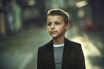 Obraz premium elegantly dressed handsome boy standing and walking the streets of the city