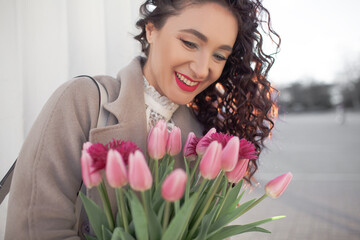 the portrait of 35 years old woman is walking with a bouquet of flowers in the spring streets of...