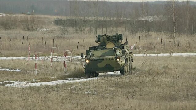 Armored personnel carriers (APC) and trucks are driving on the road. Armored wheeled vehicles on exercises in Ukraine. Armored personnel carrier performs military exercises. Military training