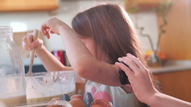 Young girl baking while older sister checks her blood sugar level 