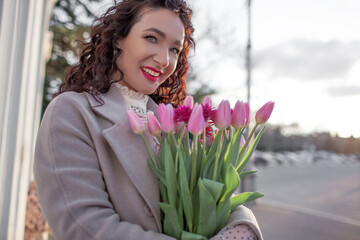 35 years old woman is walking with a bouquet of flowers in the spring streets of the city