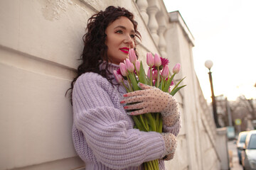 portrait of 35 yers old woman is walking with a bouquet of flowers in the spring streets of the city