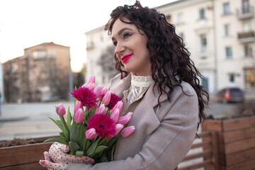 35 years old woman is walking with a bouquet of flowers in the spring streets of the city