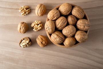 Peeled walnuts and whole walnuts in wooden bowl,top view