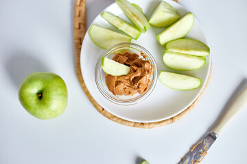 Green slices apples with peanut butter on white background, healthy snack, nutrition food, diet