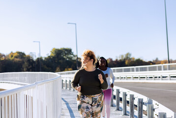 Two young plus size women jogging together.