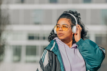 girl with headphones and sunglasses listening to music on the street