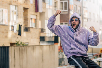 young man on the street in sportswear celebrating euphoric