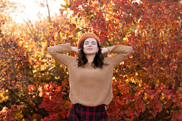 Beautiful young woman relaxing at park during autumn season. In a park with red foliage in...