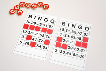 Many wooden chips with numbers and cards for a board game of bingo or lotto on a light background.