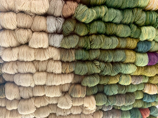 A background of skeins of wool in natural tones and green shades.