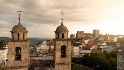 Obraz premium Bell tower at dawn of a church in the background at the top of the village you can see a fortress.
