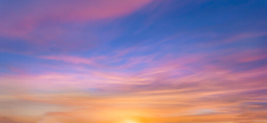 Obraz premium Real amazing panoramic sunrise or sunset sky with gentle colorful clouds. Long panorama, crop it. Evening sky scene with golden light from the setting sun