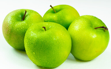 Four Juicy Green Apples, whole and isolated on white with dew drops.