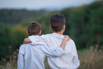 two brothers stand in each other's arms in the park