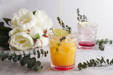 Faceted cocktail glass with crushed ice and lime into which orange juice is poured