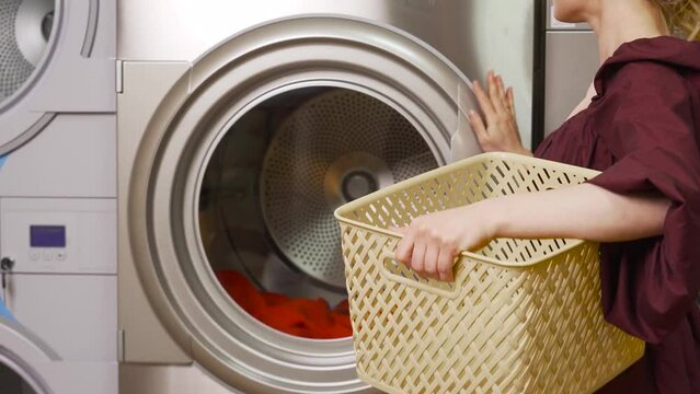 a girl in a dress throws her bright clothes into the washing machine